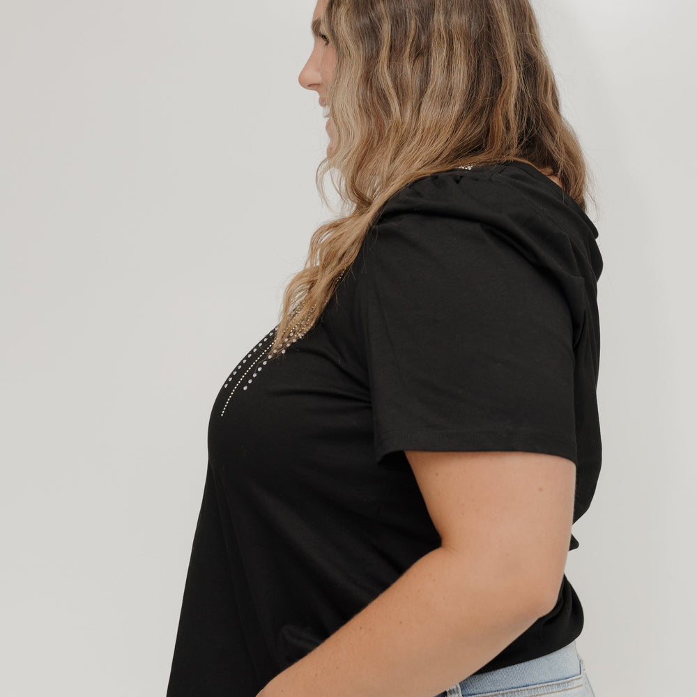 Person wearing a black hoodie and light blue jeans against a white background