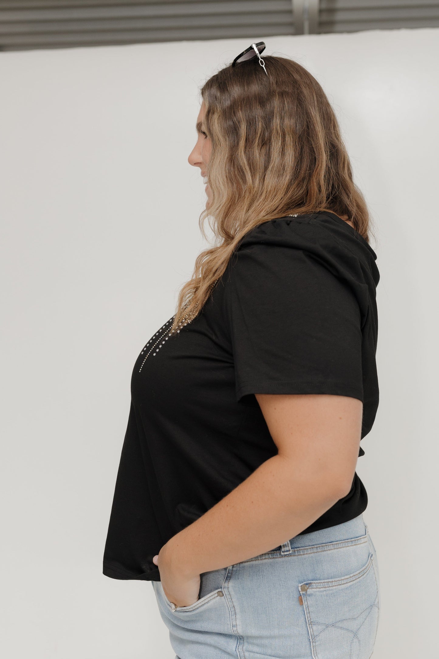 Person wearing a black hoodie and light blue jeans against a white background