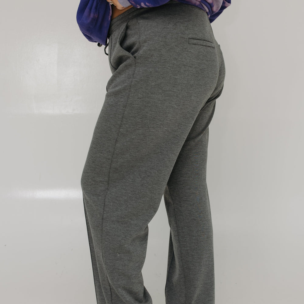 Person wearing gray sweatpants and a purple tie-dye hoodie on a white background
