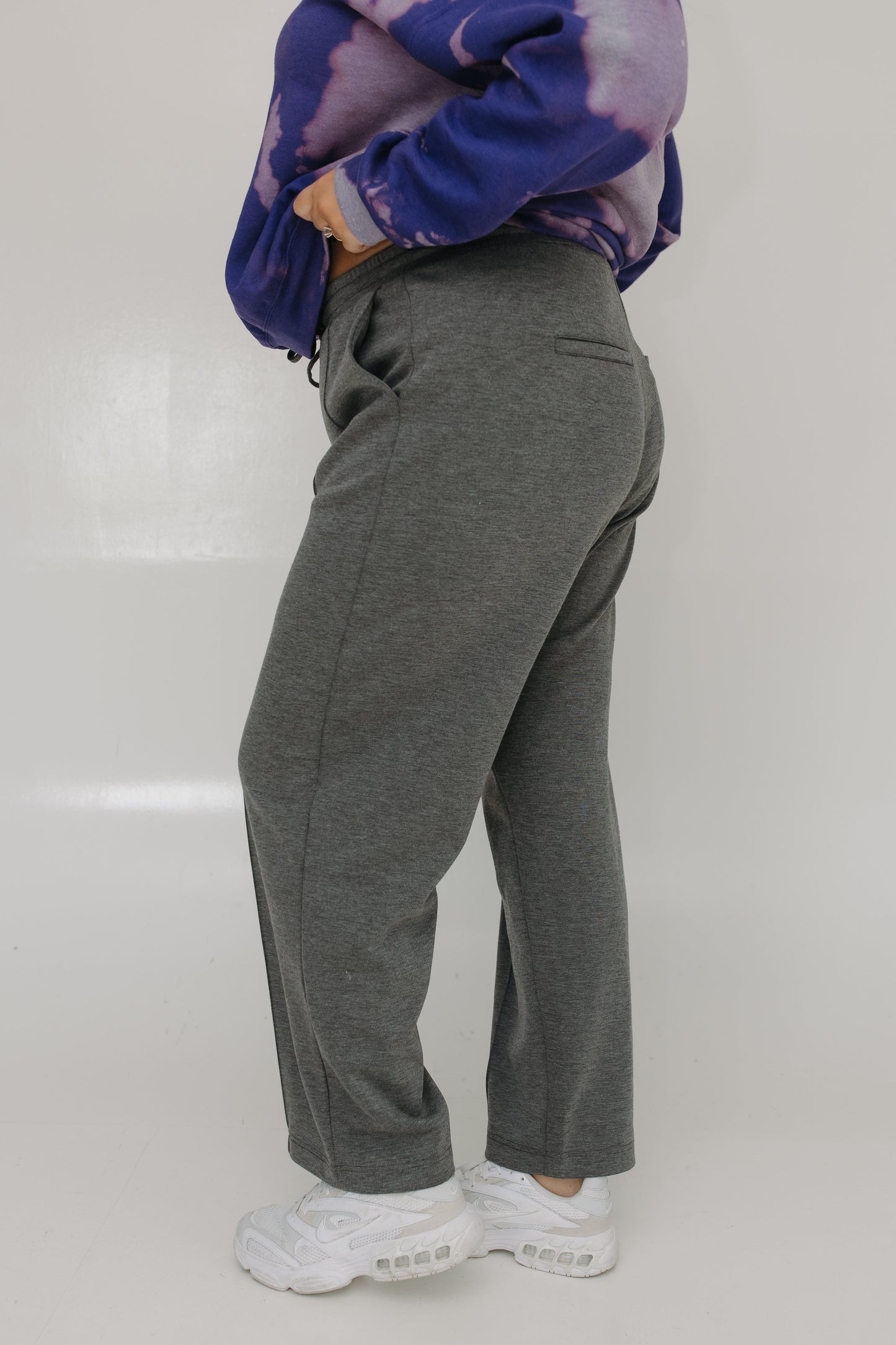 Person wearing gray sweatpants and a purple tie-dye hoodie on a white background