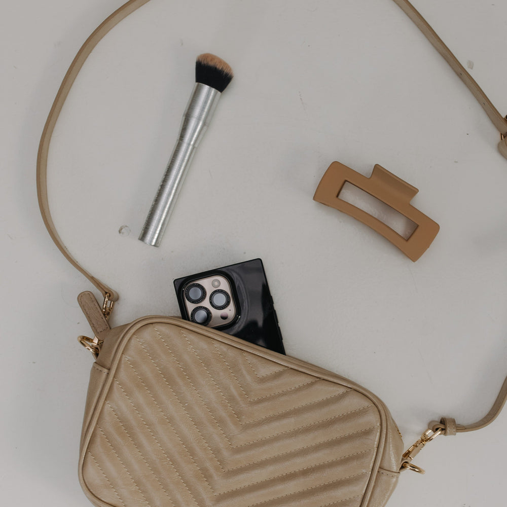 Sand handbag with makeup items on a light background