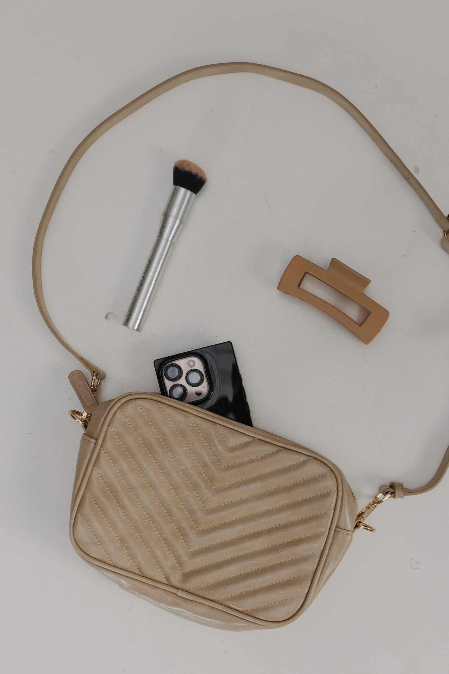 Sand handbag with makeup items on a light background