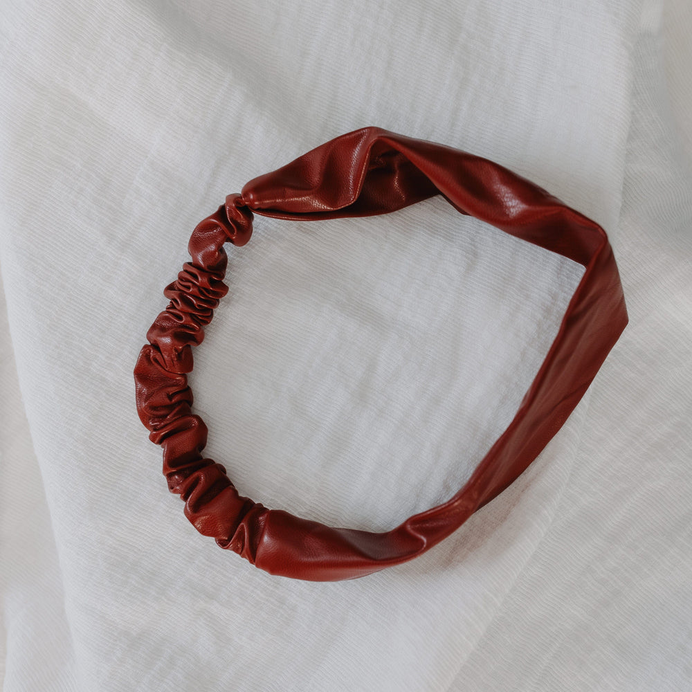 Red leather headband on a white textured fabric background