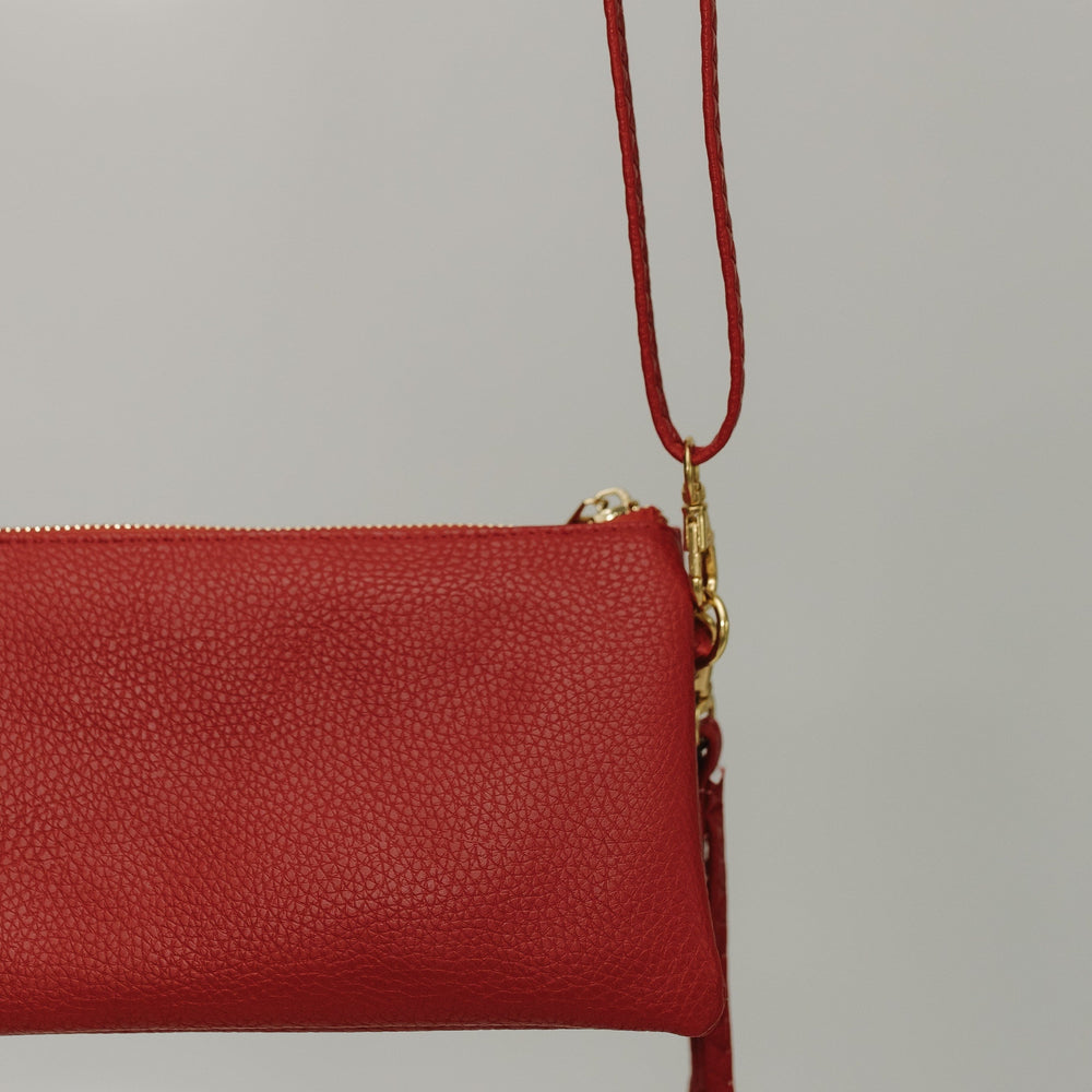 Red clutch bag with a gold zipper on a light gray background