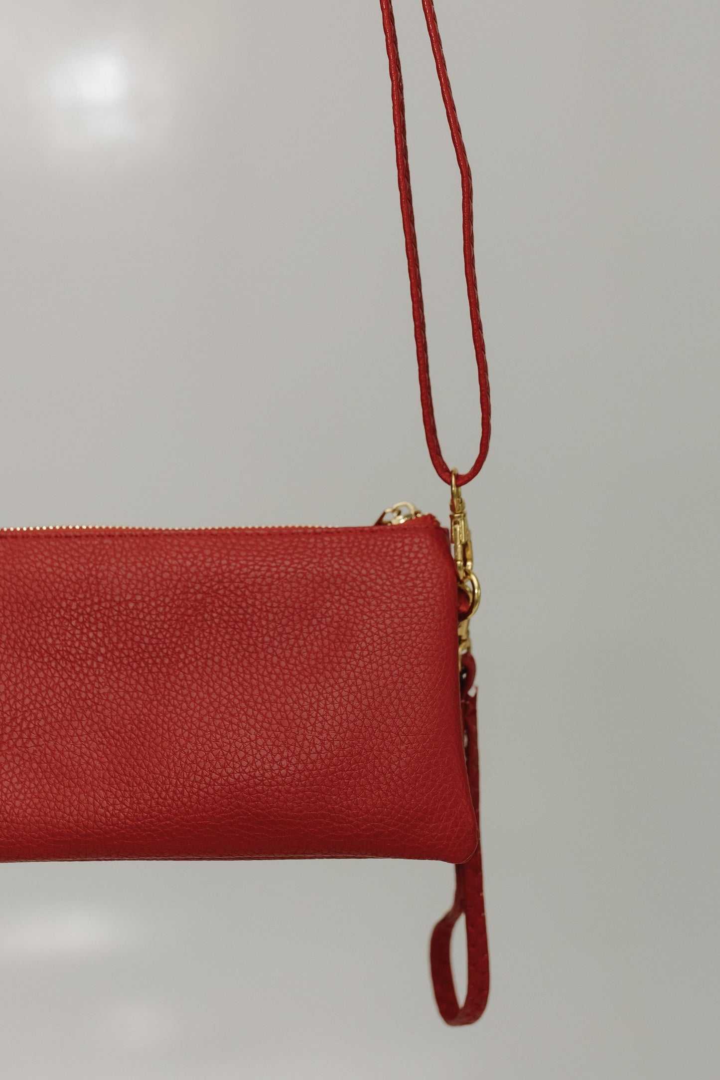Red clutch bag with a gold zipper on a light gray background