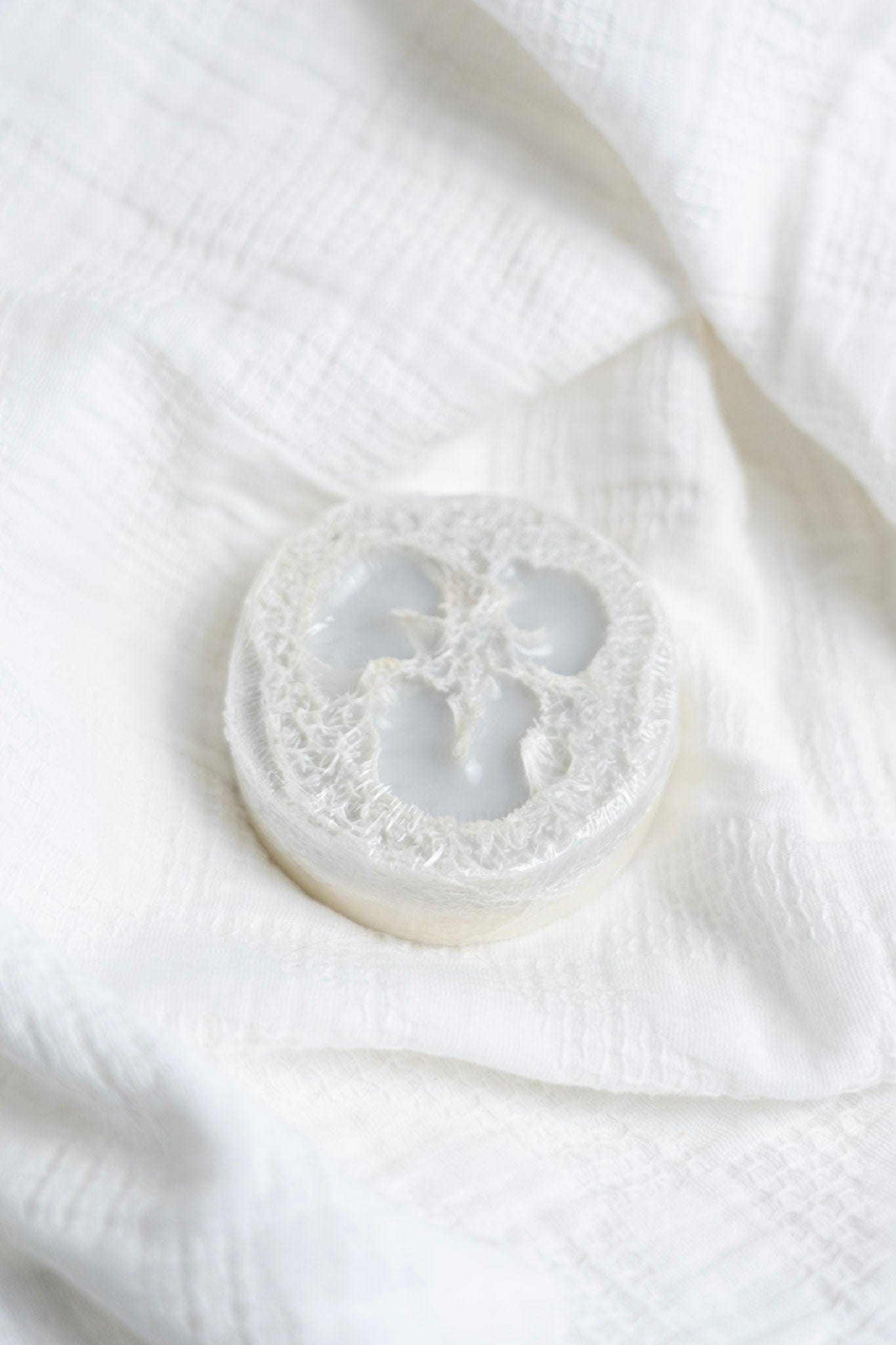 Rejuvenate loofah soap on a white fabric background