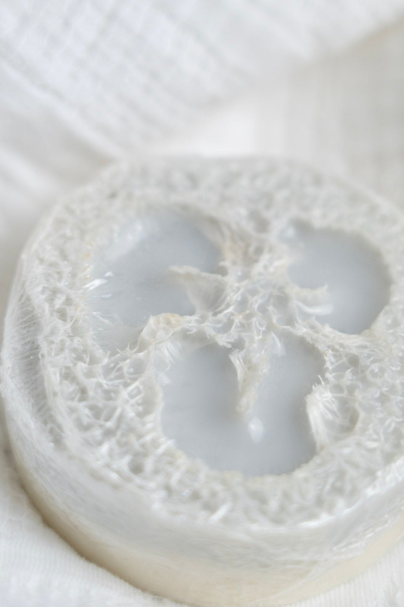 Close-up of a loofah soap on a  textured white fabric with a circular pattern