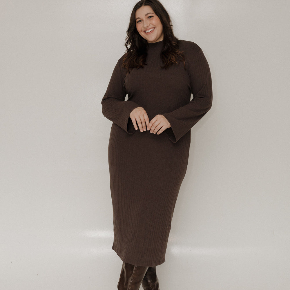 Woman wearing a brown dress and boots against a white background