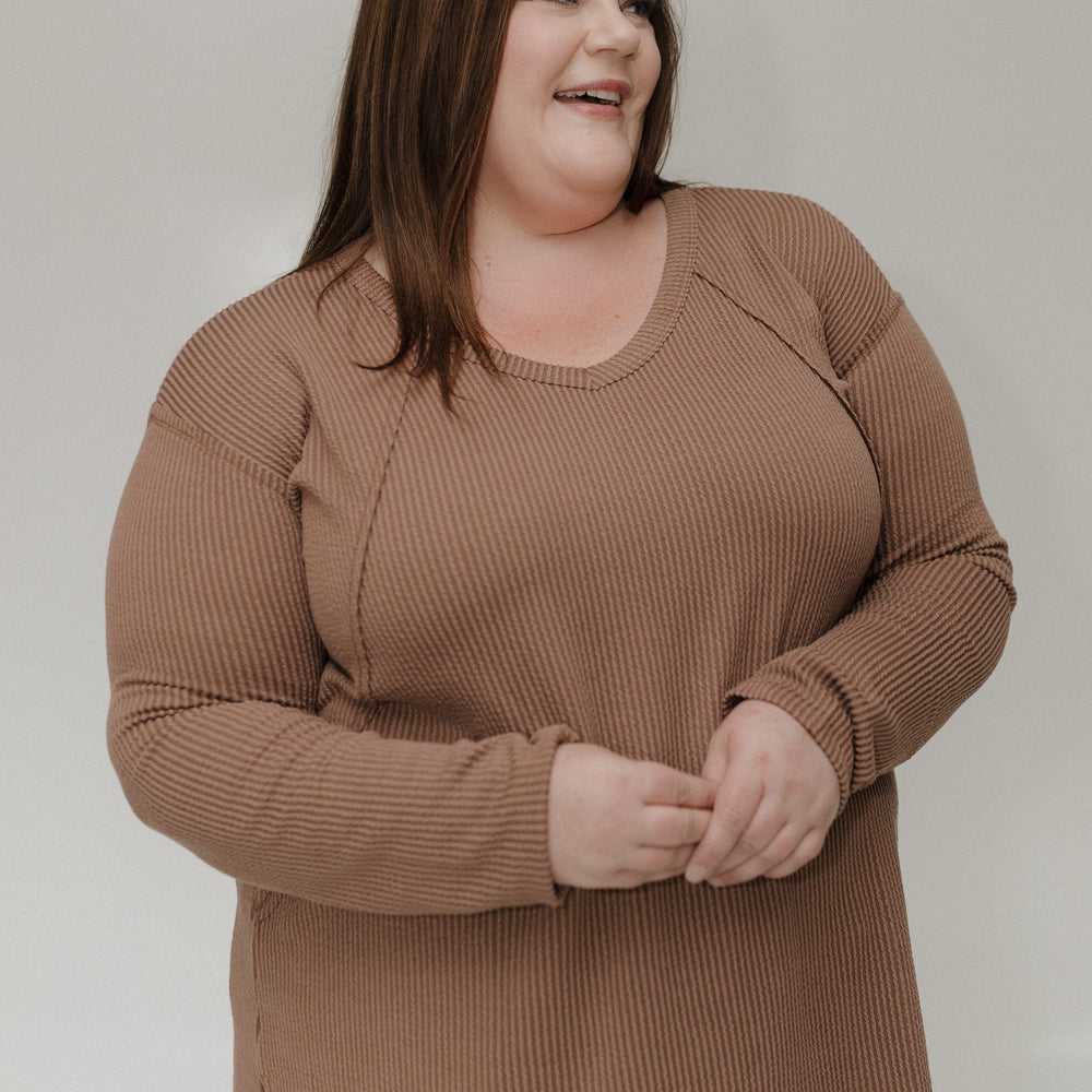 Woman wearing a brown tee against a plain background