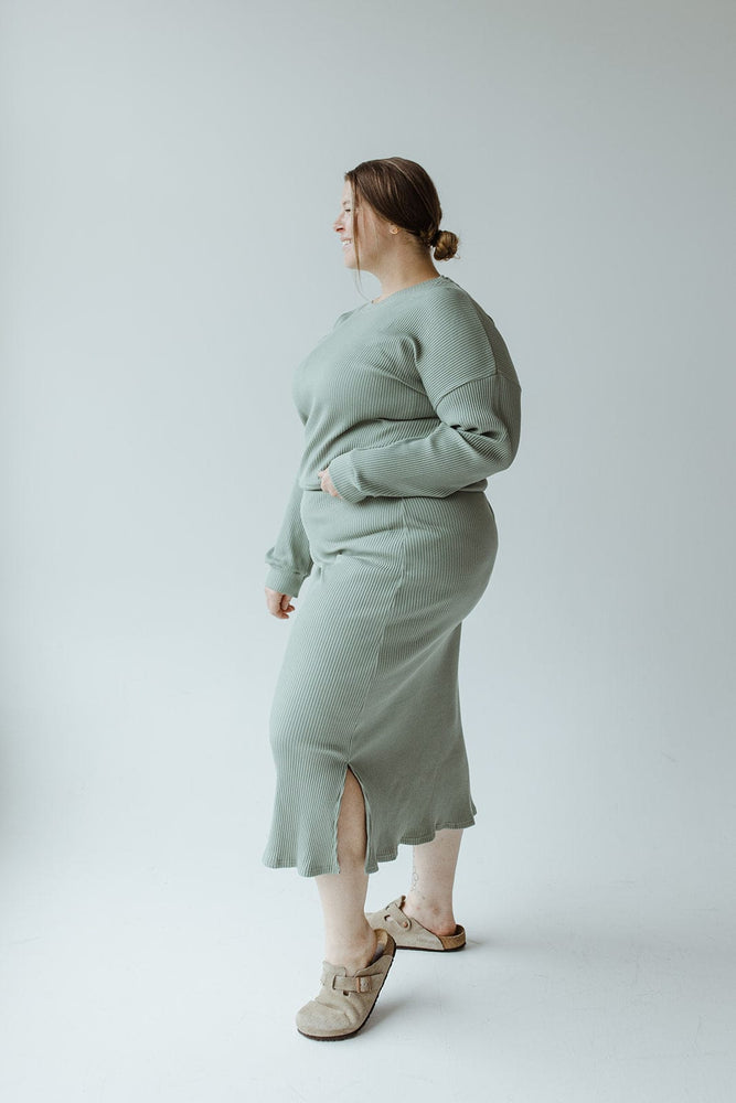 A person wearing the Mikarose Ribbed Cropped Sweater in Faded Jade, featuring dolman sleeves, is viewed from behind against a plain background.