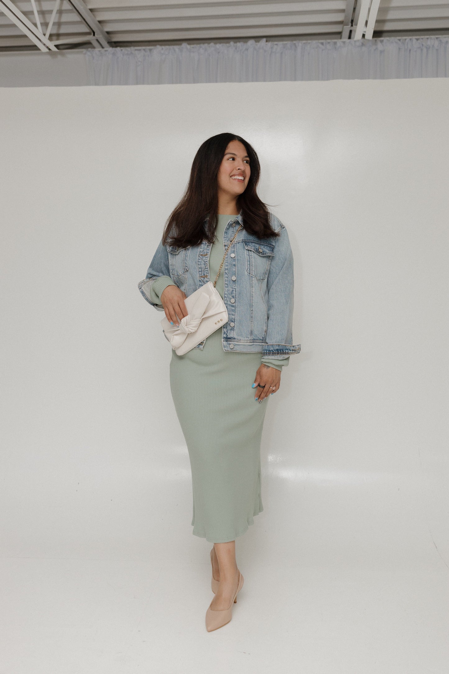Woman wearing a denim jacket and green skirt with a white background