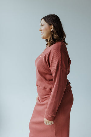 Side profile of a person with shoulder-length hair wearing the RIBBED CROPPED SWEATER IN SMOKEY ROSEWOOD by Mikarose, featuring dolman sleeves, standing against a plain white background.