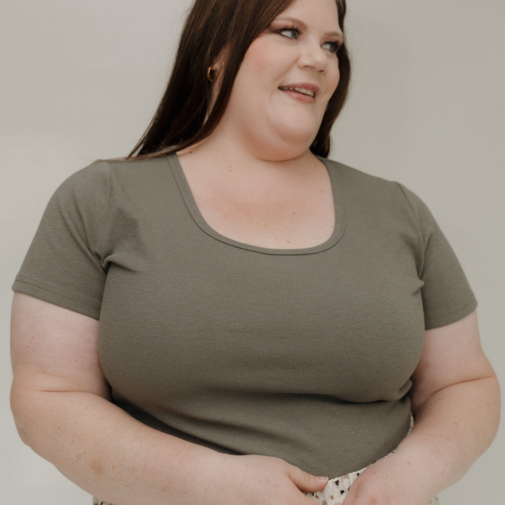 Woman wearing a green t-shirt and patterned skirt against a plain background