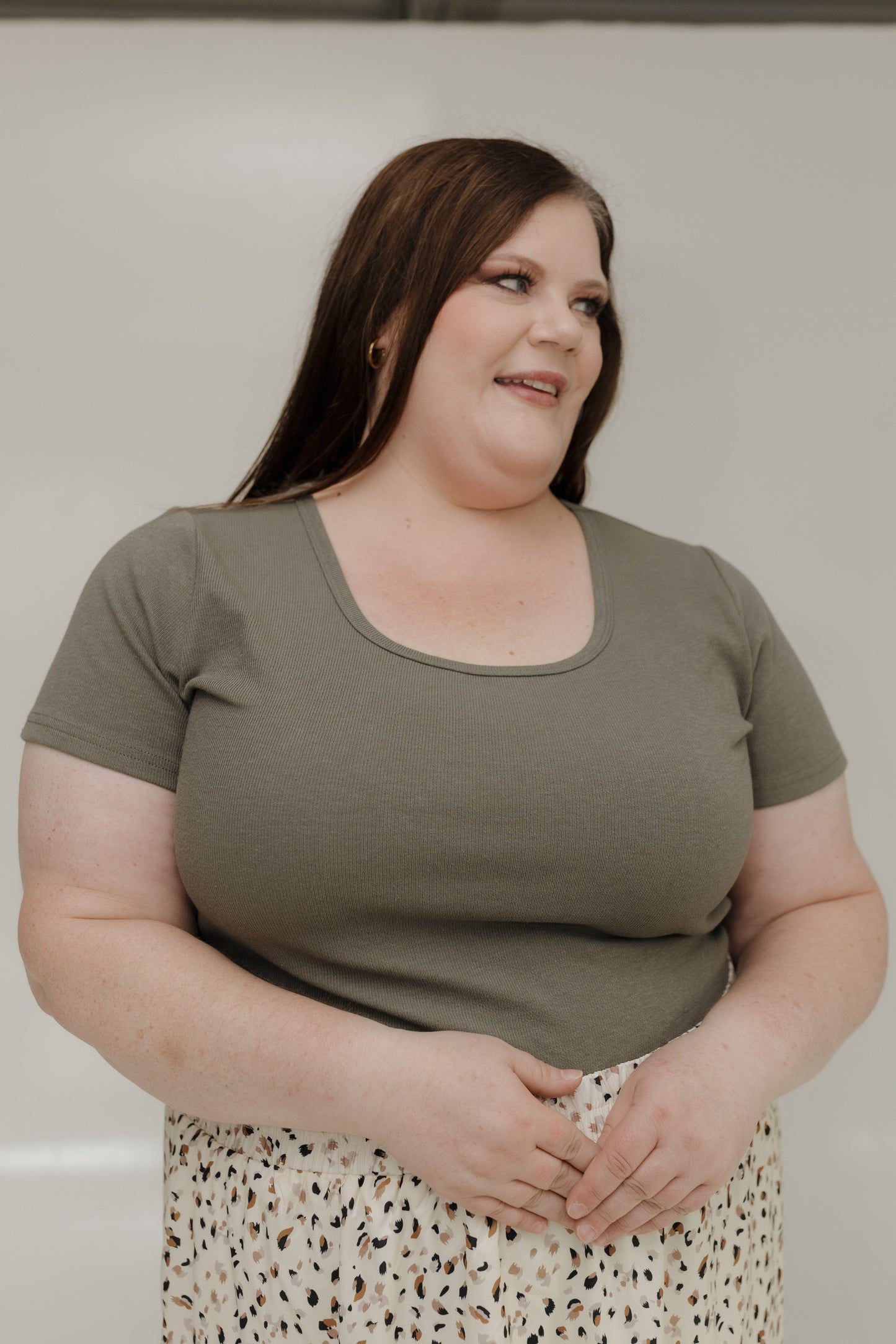 Woman wearing a green t-shirt and patterned skirt against a plain background