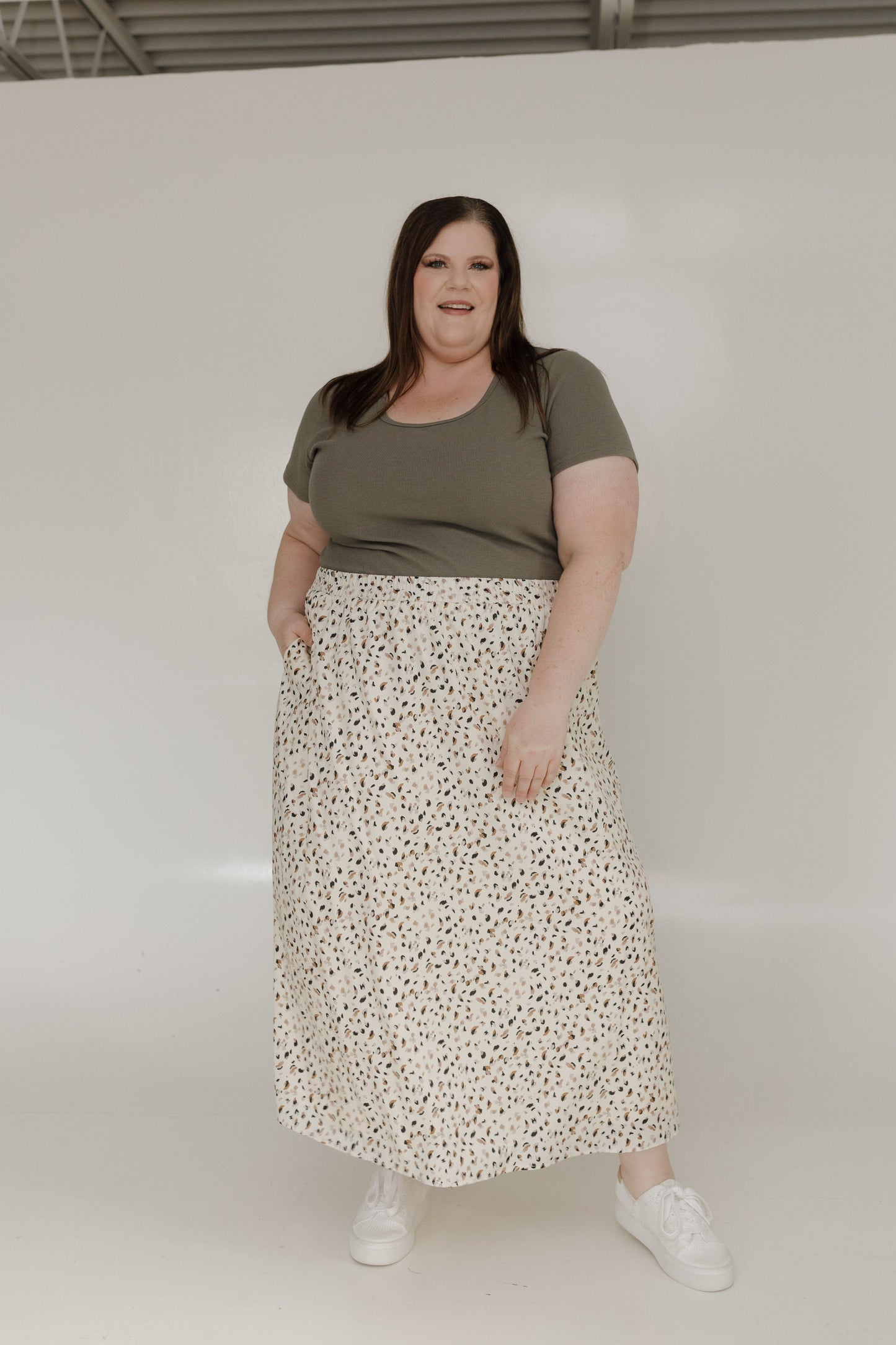 Woman wearing a green top and floral skirt on a white background