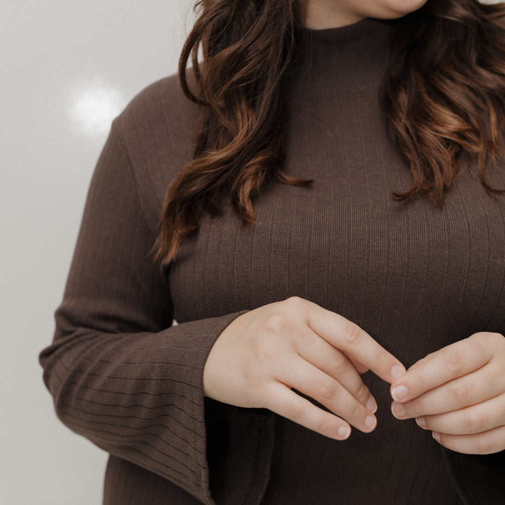 Woman wearing a brown sweater against a plain background