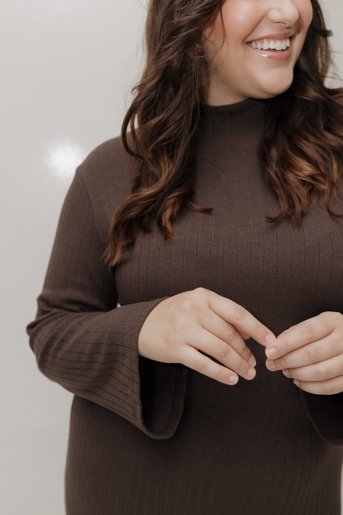 Woman wearing a brown sweater against a plain background