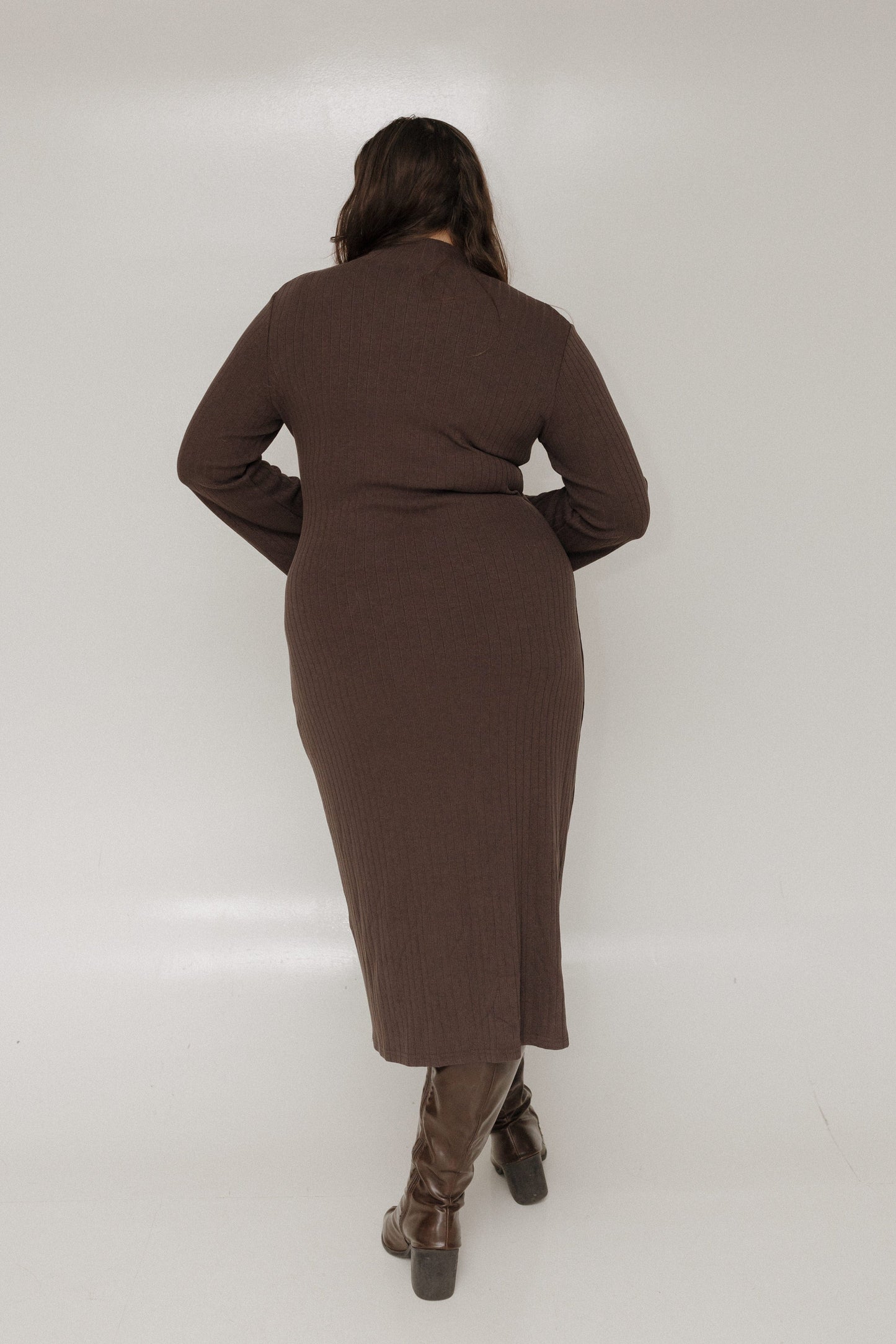 Person wearing a brown dress standing against a white background