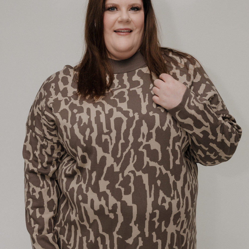 Person wearing a brown camouflage sweater against a plain background