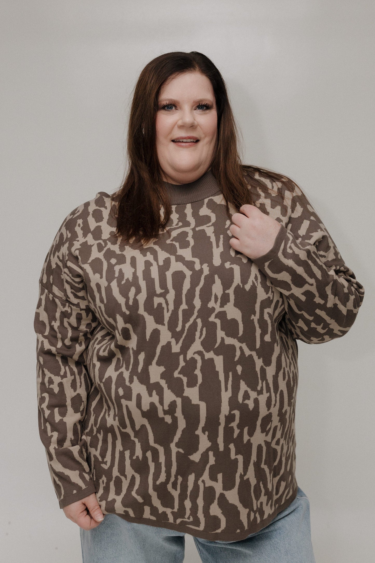 Person wearing a brown camouflage sweater against a plain background