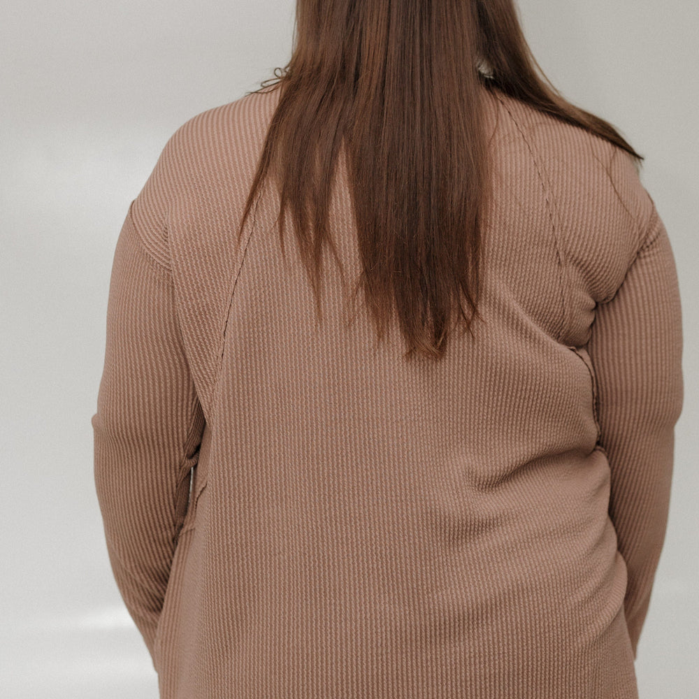 Person wearing a brown tee against a plain background