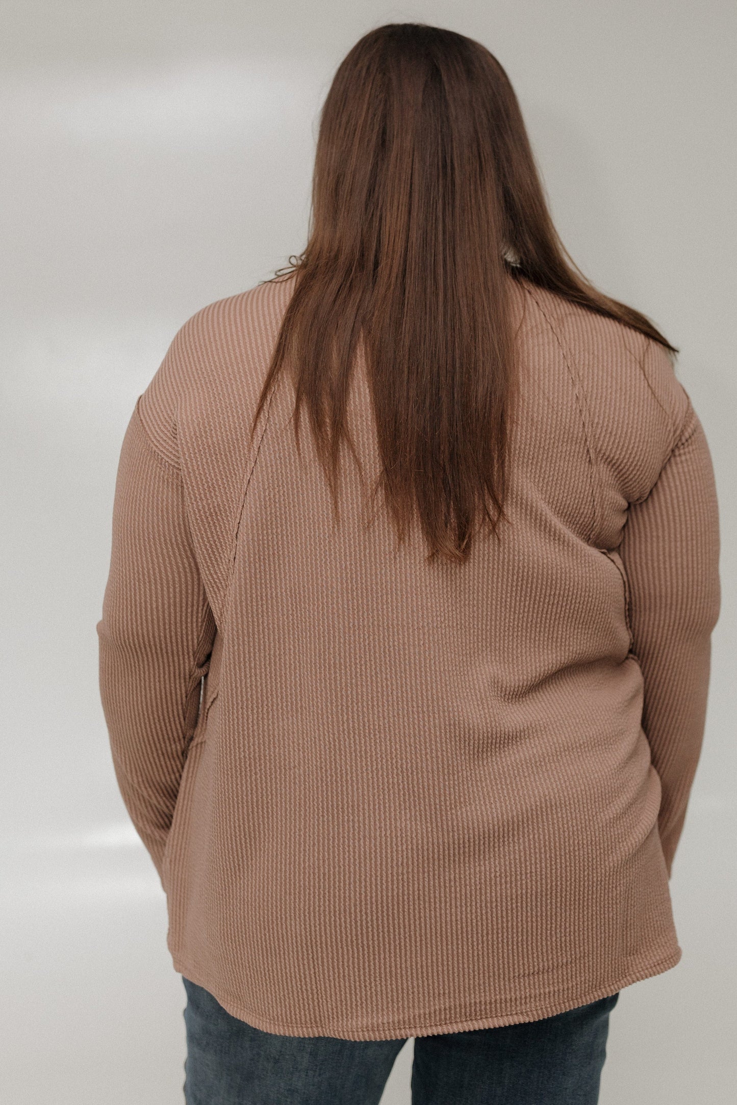 Person wearing a brown tee against a plain background