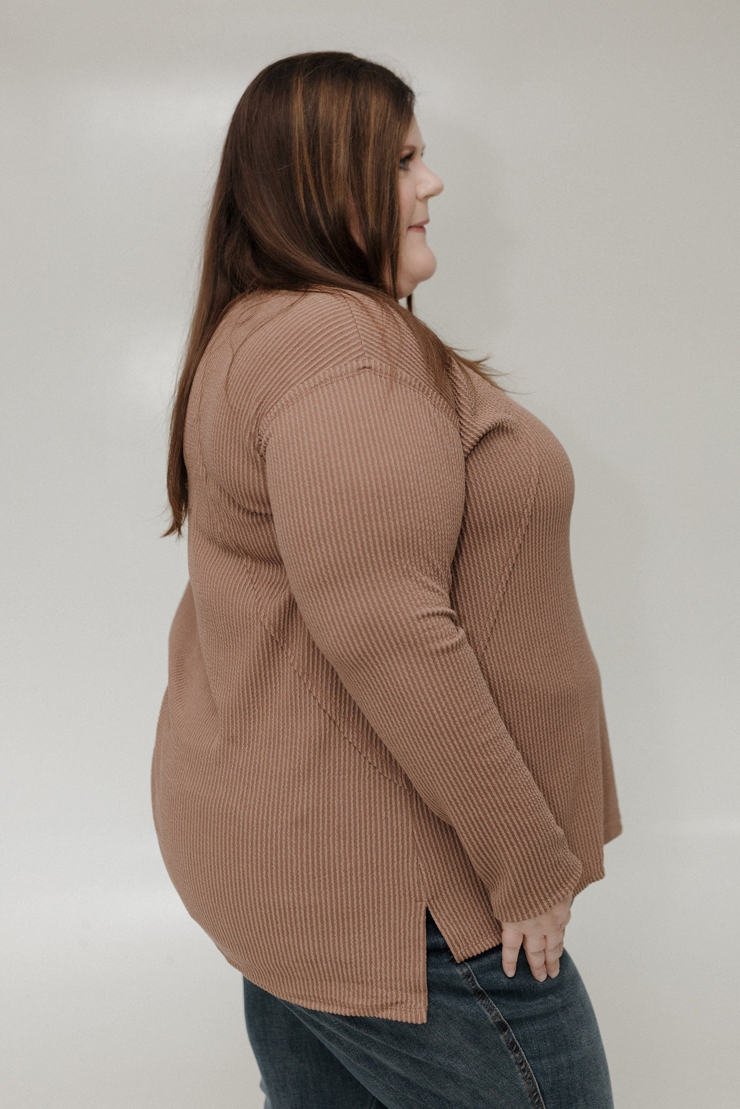 Woman wearing a brown ribbed tee against a plain background