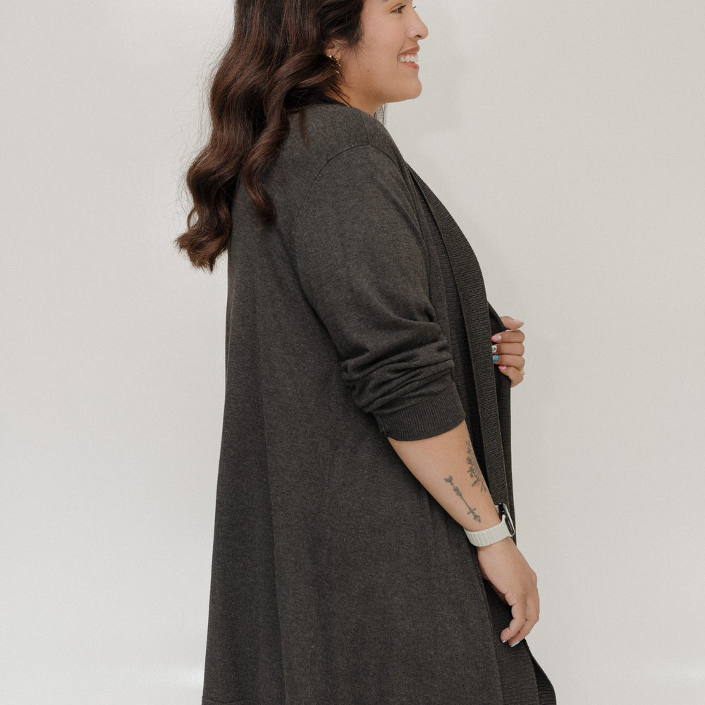 Woman wearing a dark gray cardigan against a white background