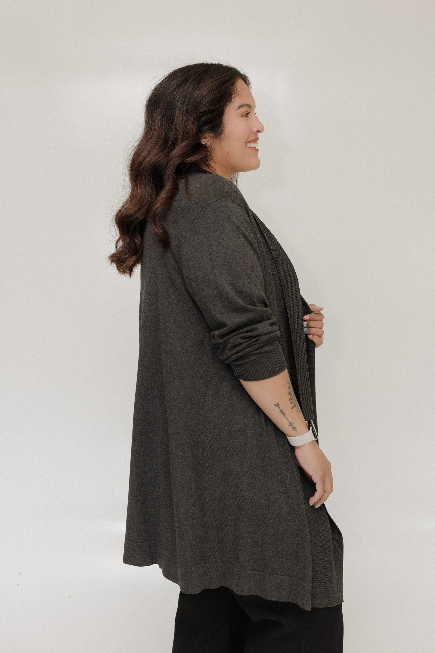 Woman wearing a dark gray cardigan against a white background