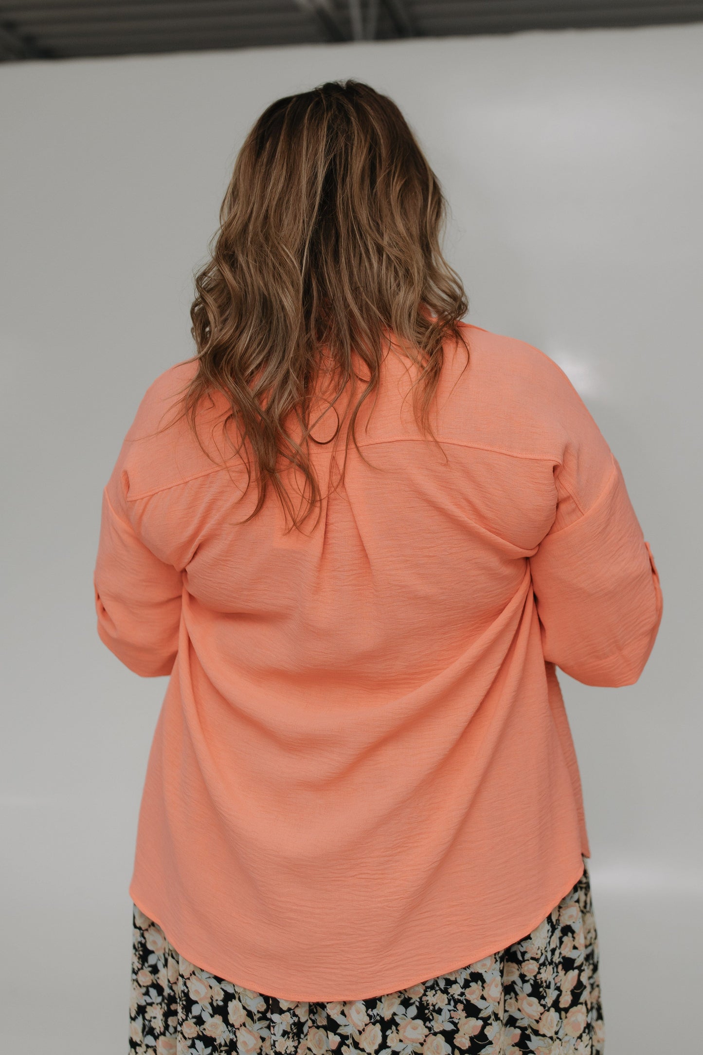 Person wearing a peach-colored shirt with a plain background