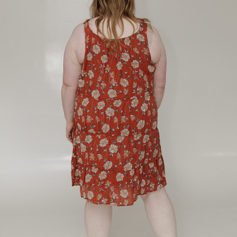 Person wearing a red floral dress against a white background
