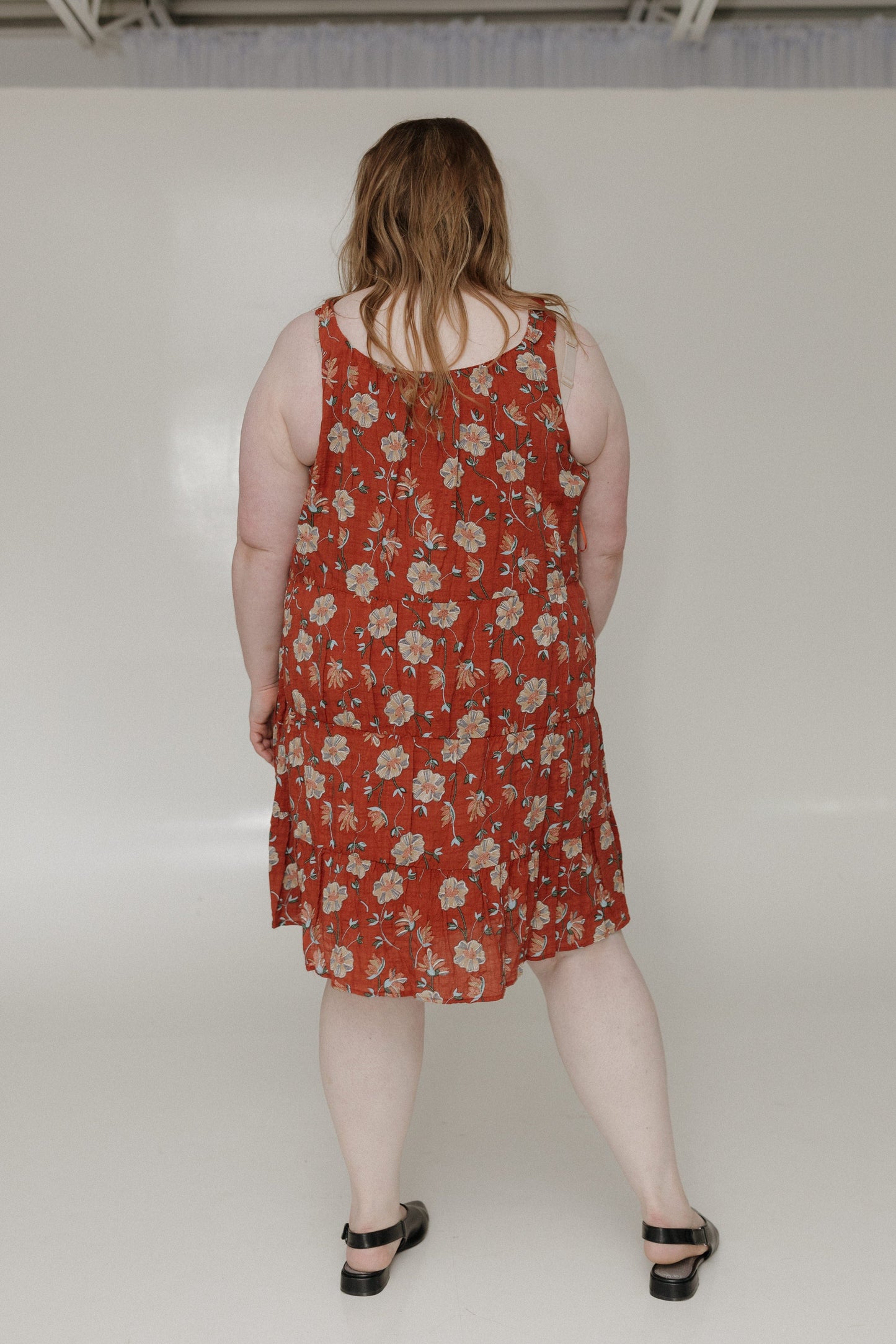 Person wearing a red floral dress against a white background