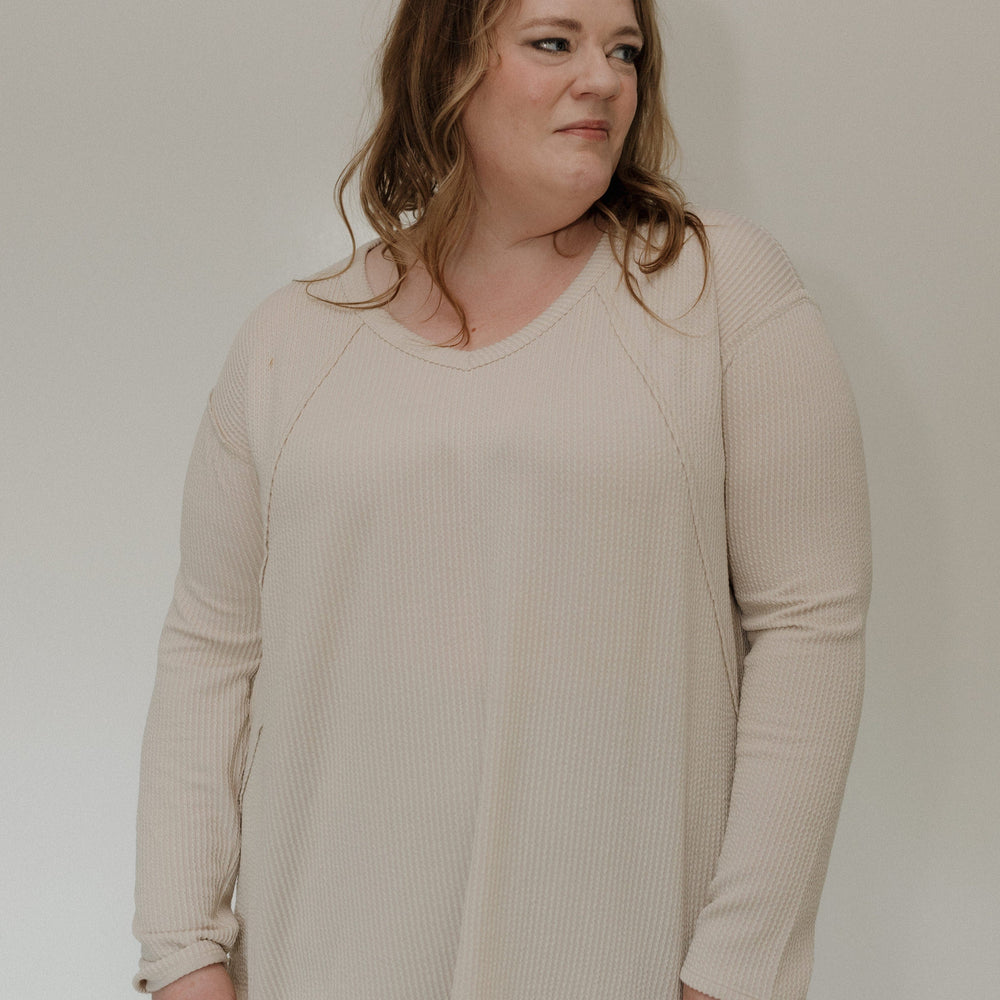 Woman wearing a sand shirt against a plain background