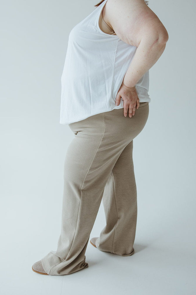 A person in a white sleeveless top and Yesta's LIGHT KHAKI STRAIGHT LEG PULL-ON PANT is standing sideways with one hand on their waist, against a plain, light-colored background.