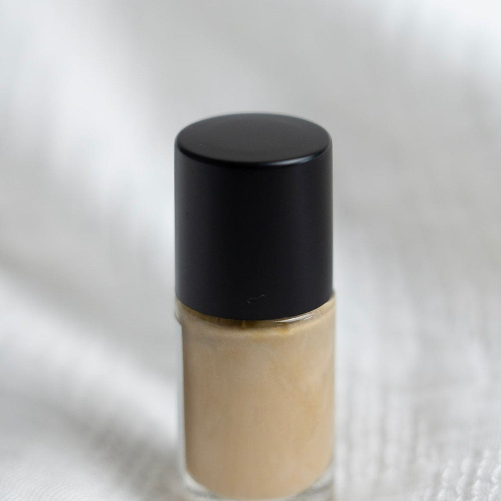 Small glass bottle with a black cap on a white textured background