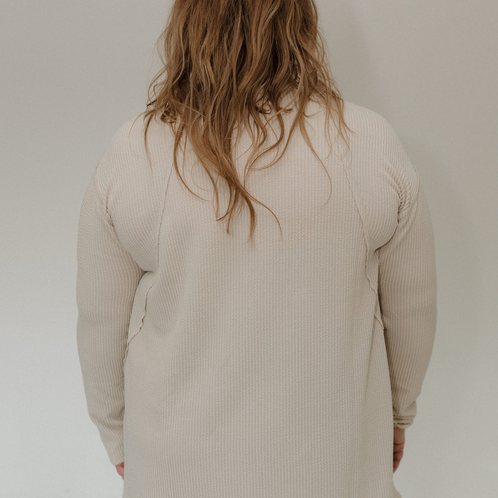 Person wearing a sand ribbed shirt against a plain background