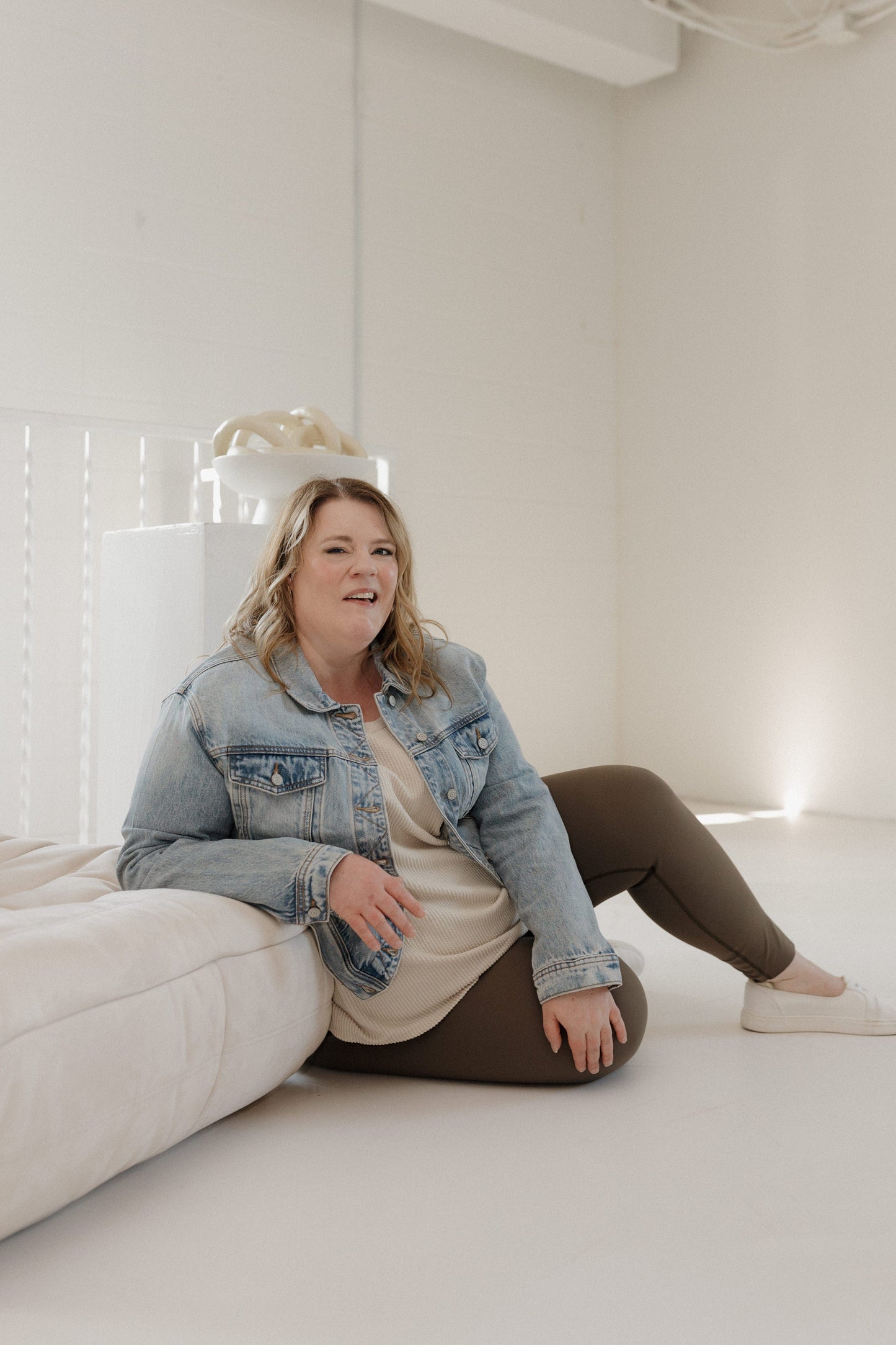 Woman sitting on a white couch in a minimalistic room