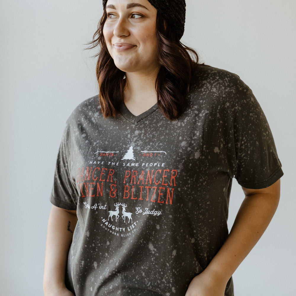 Person wearing a dark speckled t-shirt with festive reindeer names, showcasing their holiday spirit, and a black headband, standing against a light background.