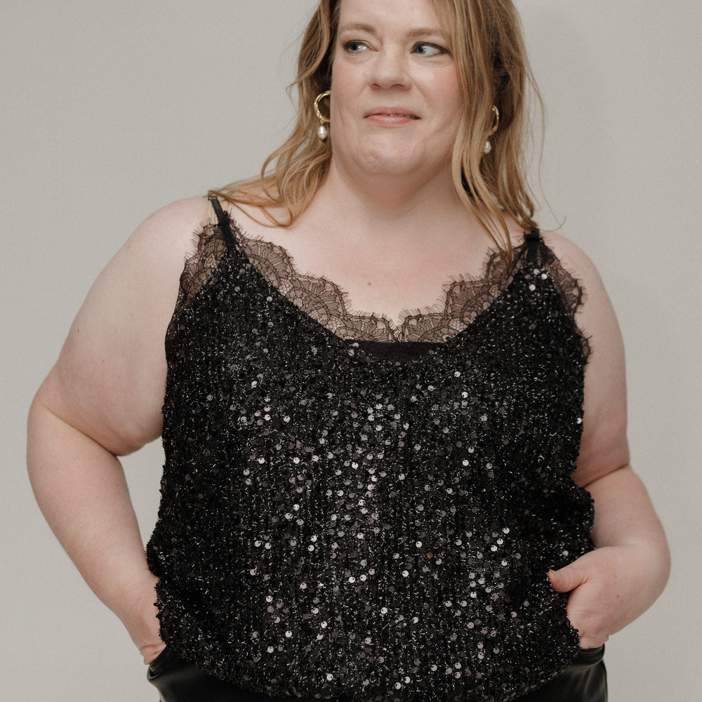 Woman wearing a black sequin top against a plain background