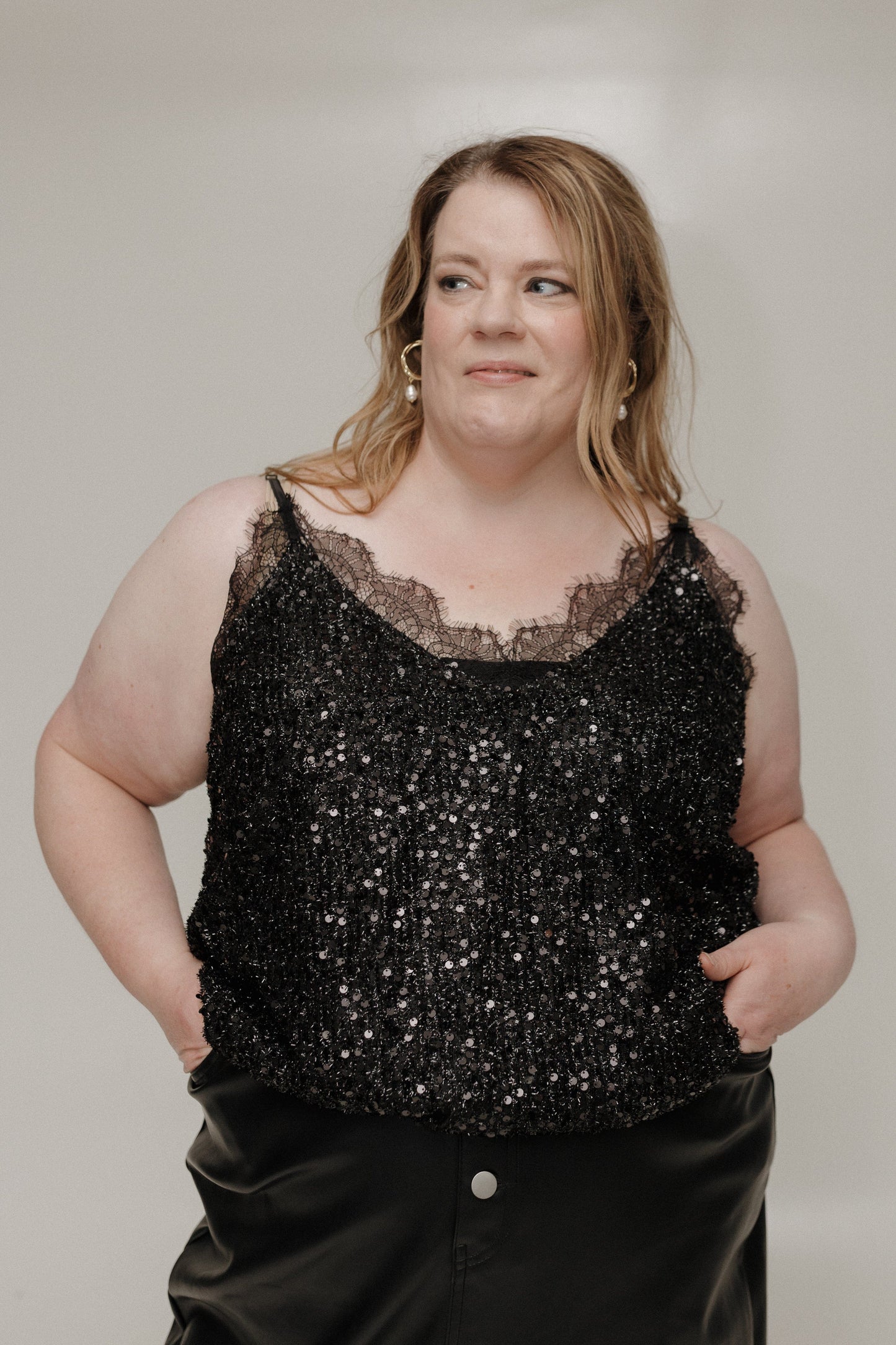 Woman wearing a black sequin top against a plain background