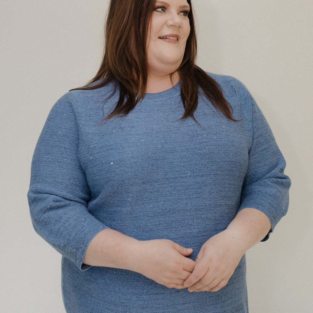 Woman wearing a blue sweater against a plain background