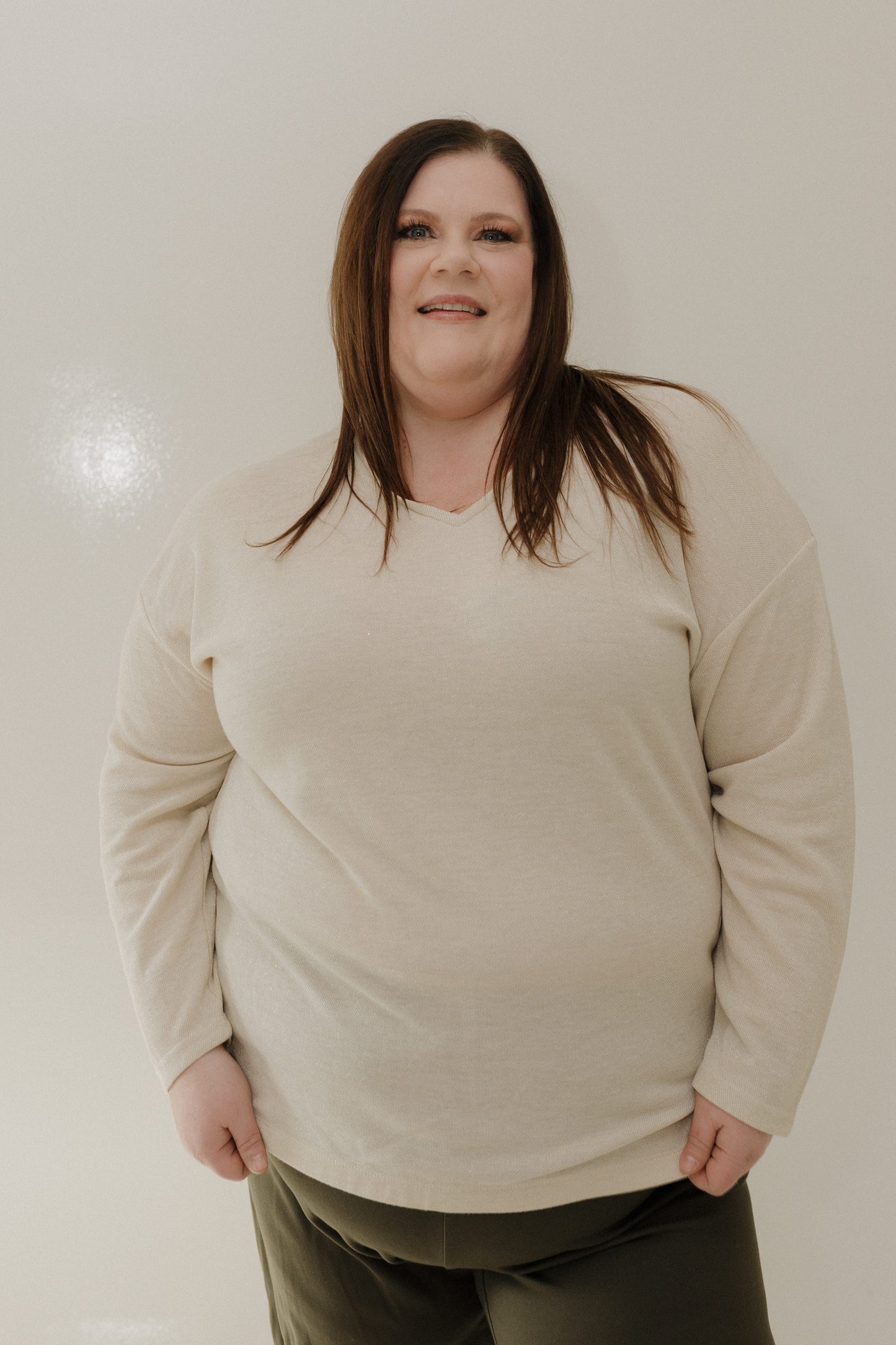 Person wearing a beige sweater against a plain background