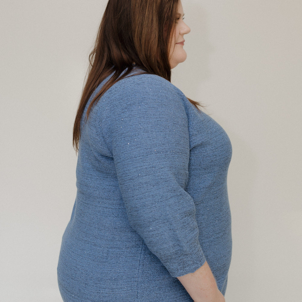 Woman wearing a blue sweater against a plain background