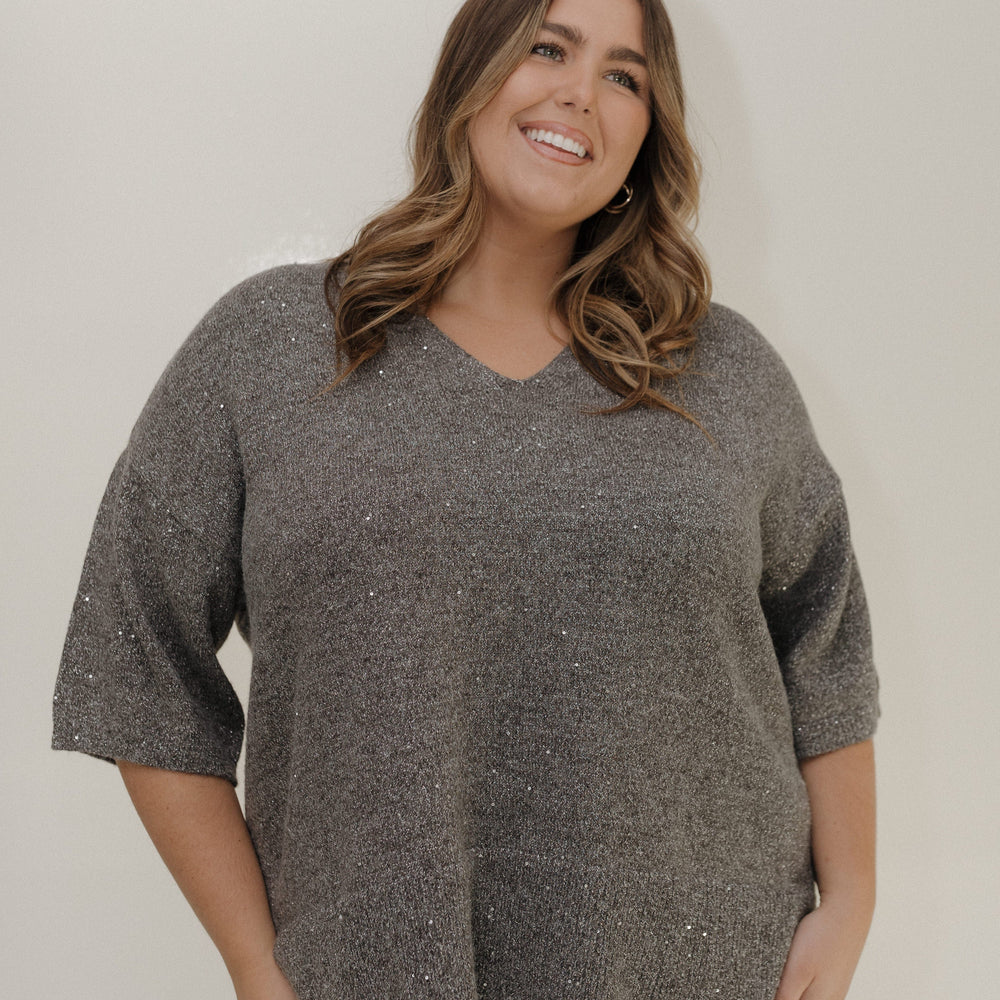 Woman wearing a gray sweater against a plain background