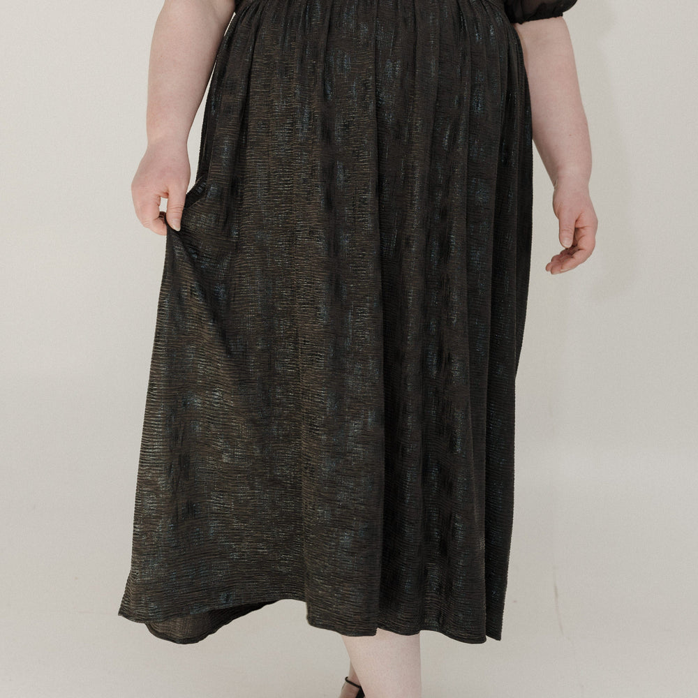 Person wearing a black top and dark gray skirt on a white background
