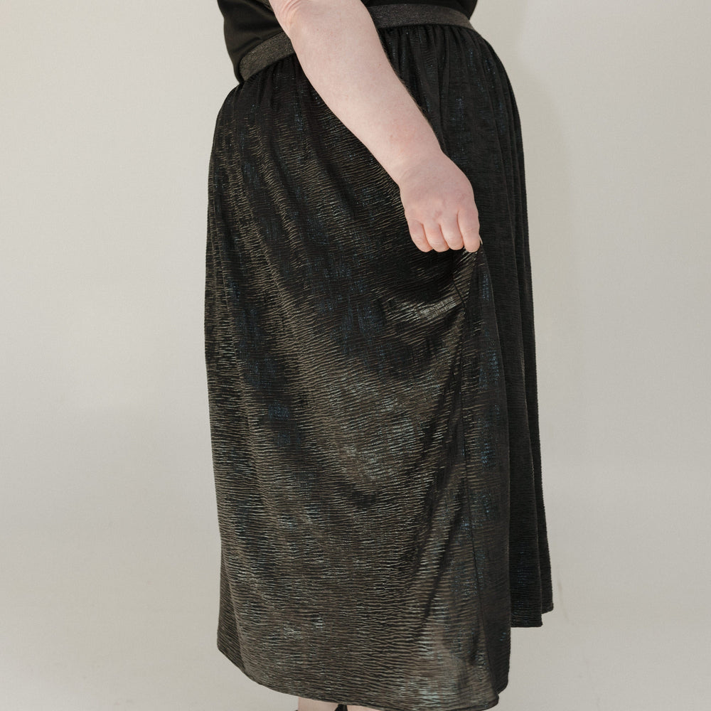 Person wearing a black dress with sheer sleeves on a plain background