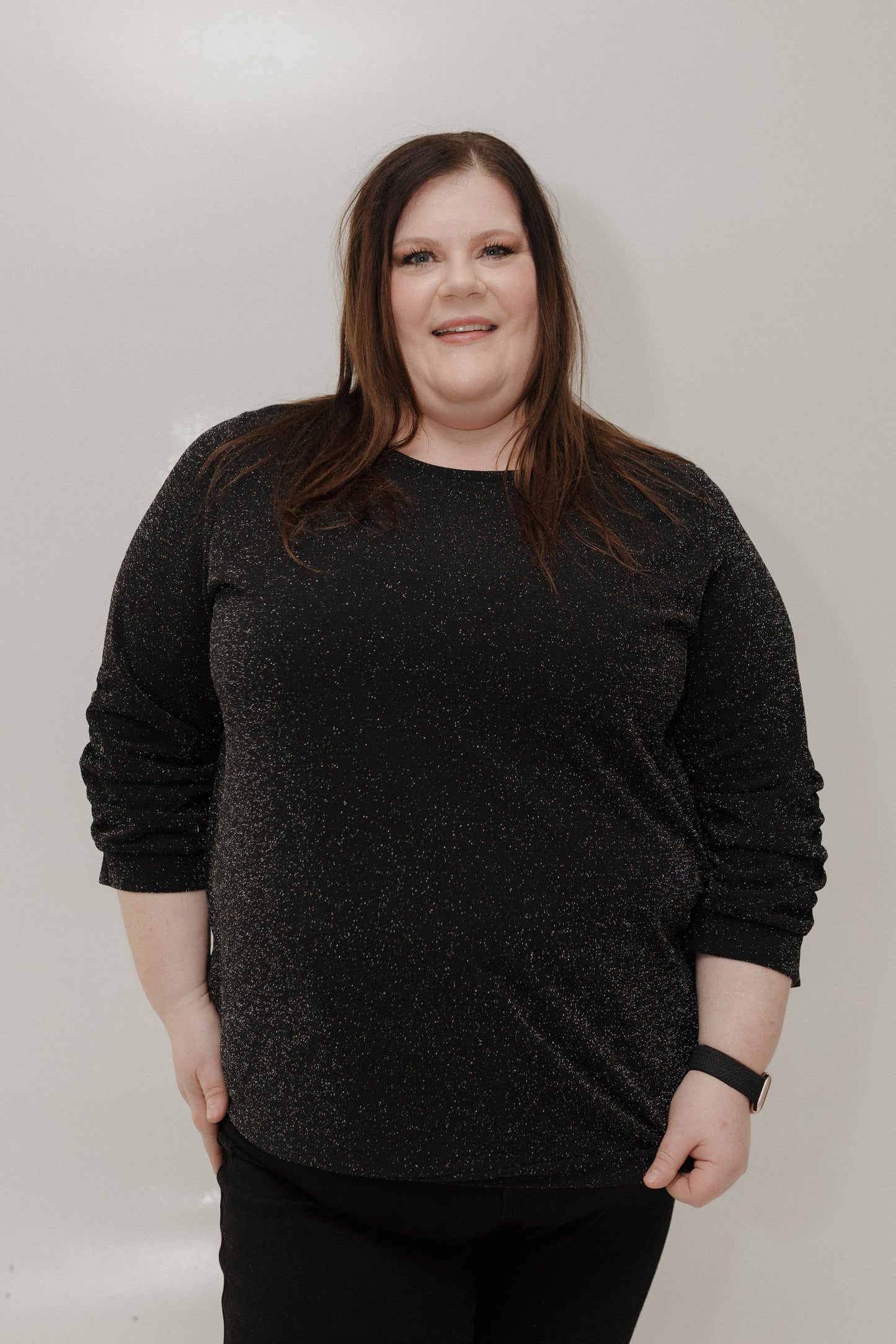 Person wearing a black sweater against a plain background