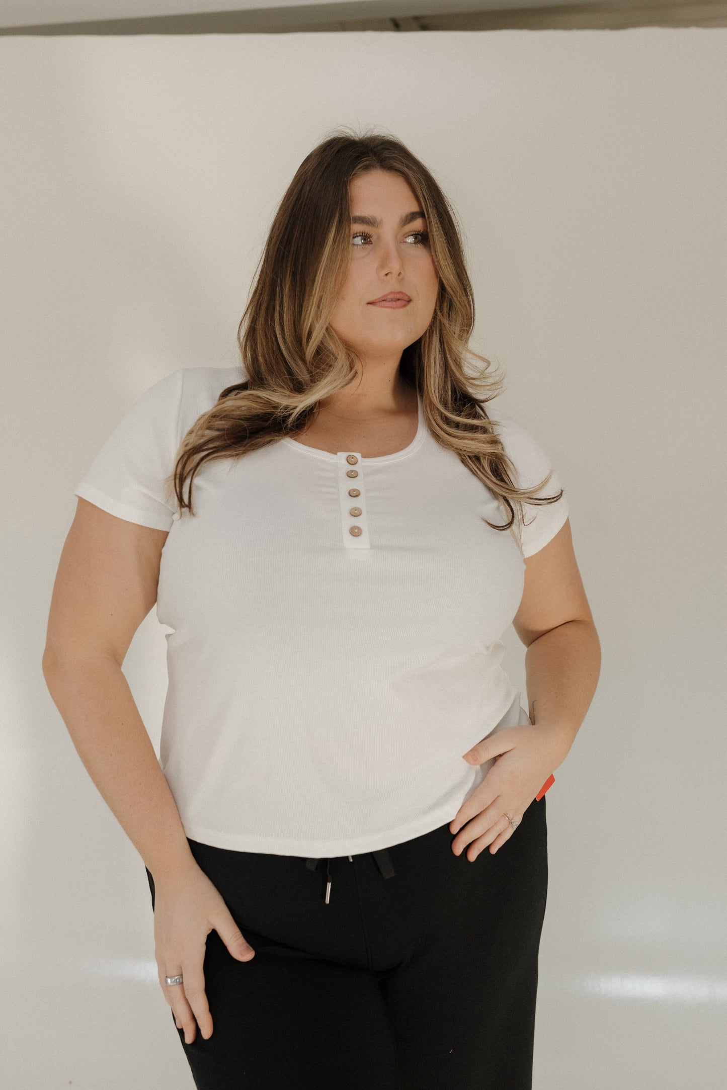 Woman wearing a white short-sleeve shirt with buttons against a plain background