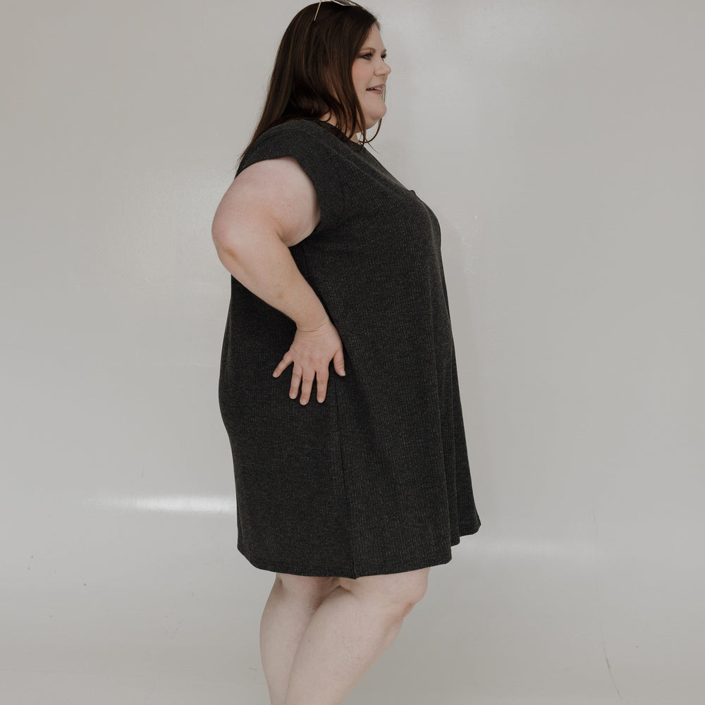 Woman wearing a black dress standing against a plain white background