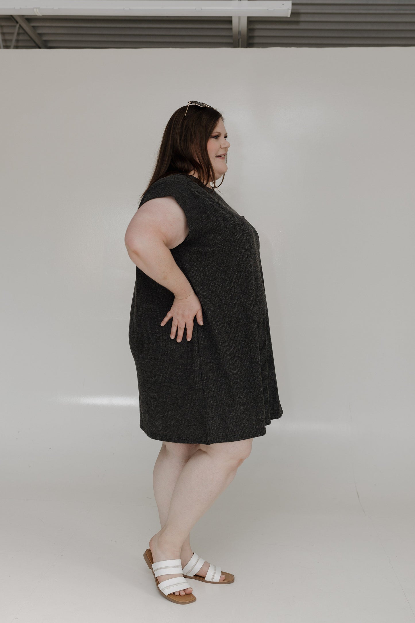 Woman wearing a black dress standing against a plain white background